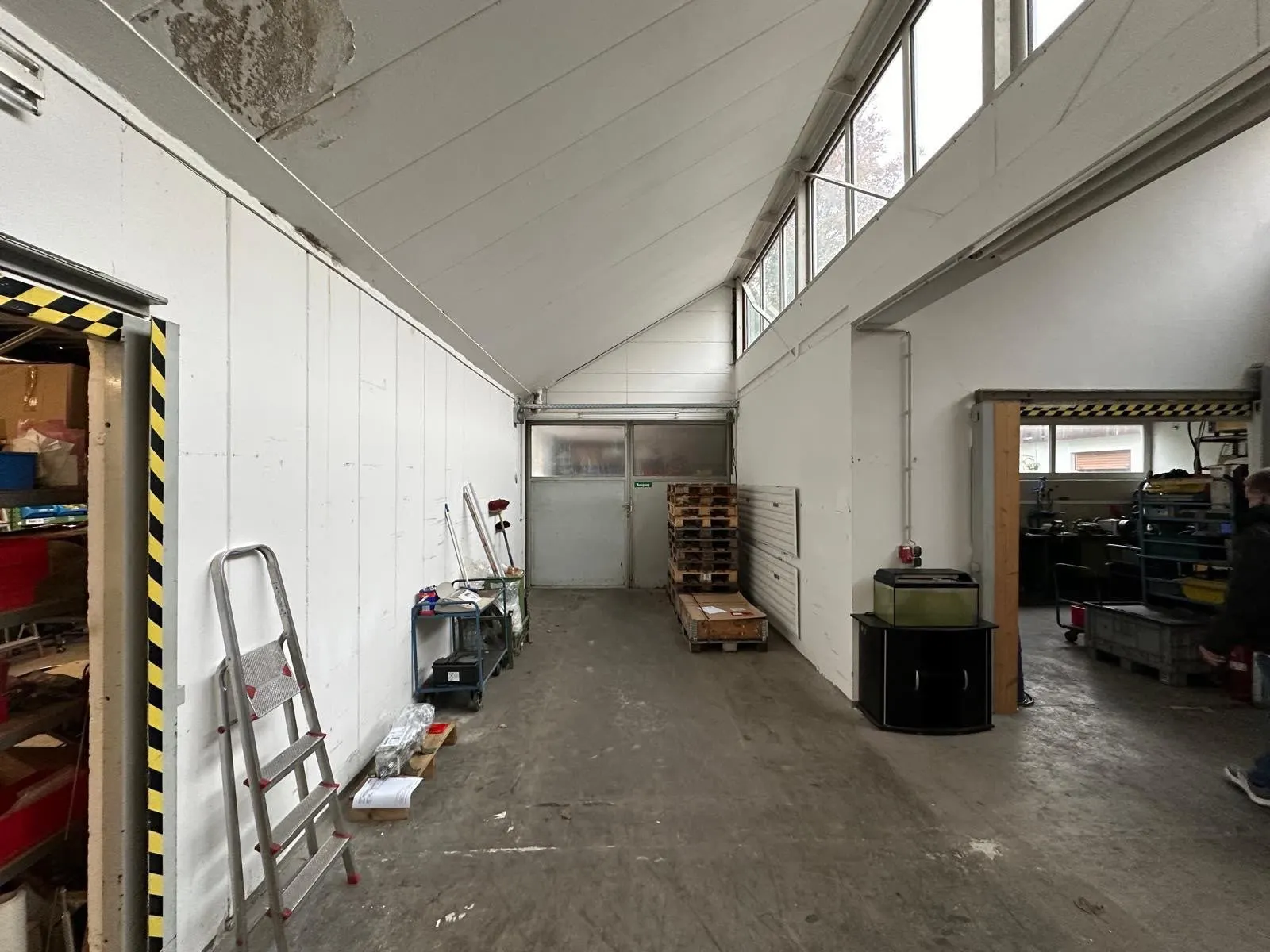 Werkstatthalle mit weißen Wänden und Betonboden vor dem Ausbau